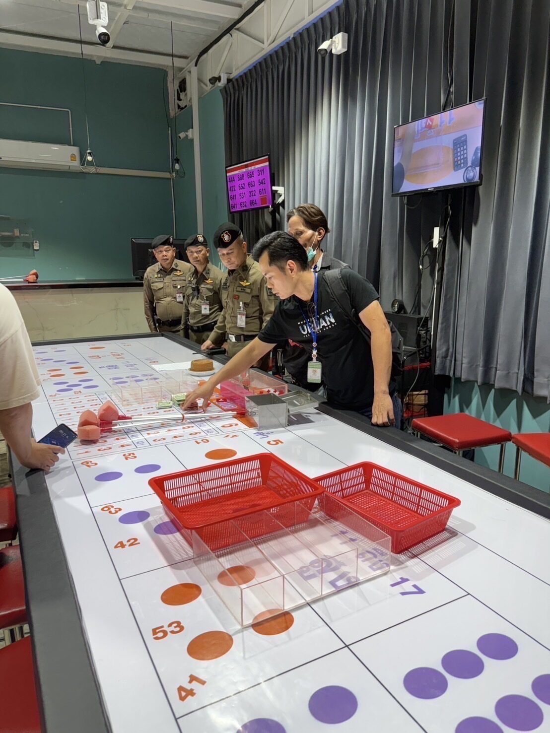Bangkok police raided a dice gambling game late at night, arresting 23 people, and all gambling equipment and cash were confiscated.